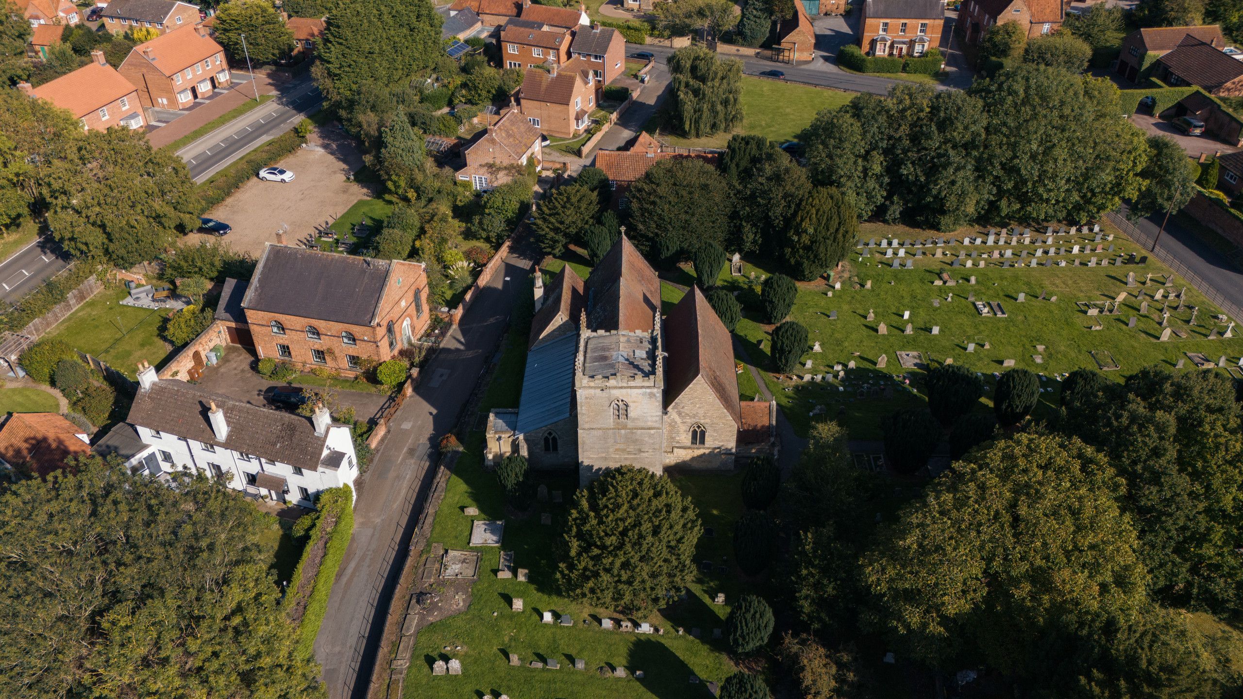 Aerial photograph of a village church and churchyard surrounded by homes and trees in Nottinghamshire