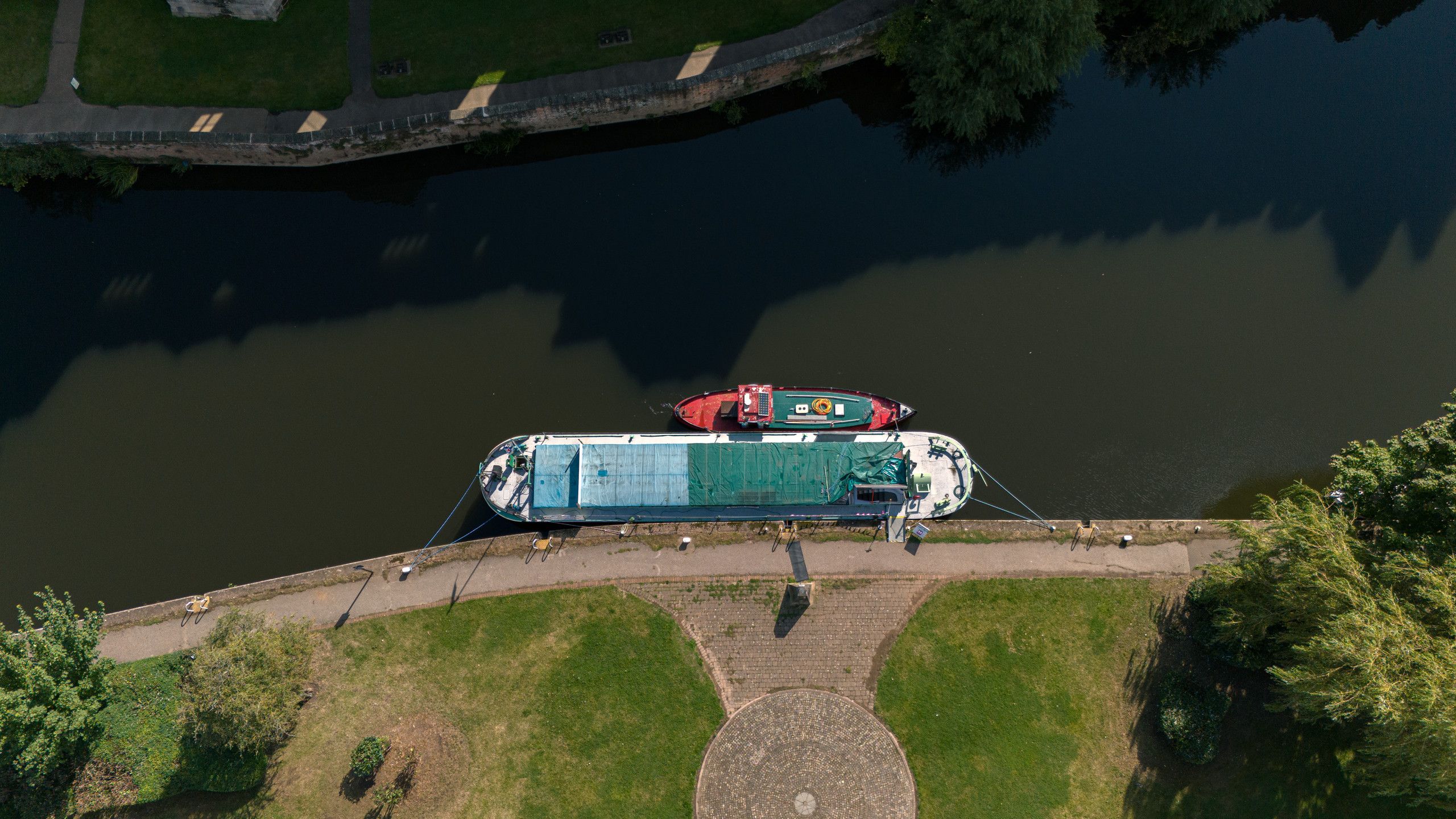 Top-down aerial photograph of two moored boats beside a stone riverbank